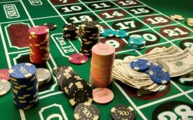 Meja permainan roulette dengan suasana kasino berkilauan di latar belakang
